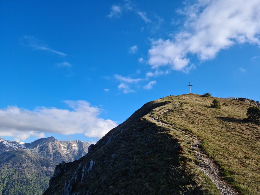 Sentiero verso la croce di vetta di Cima Durmont con le montagne sullo sfondo